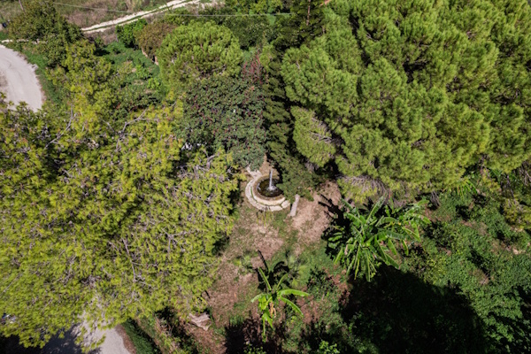 Stone well surrounded by trees and greenery at Selini Villa in Kalithea