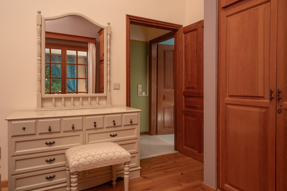 Bedroom dressing area with wooden wardrobe at Selini Villa in Kalithea